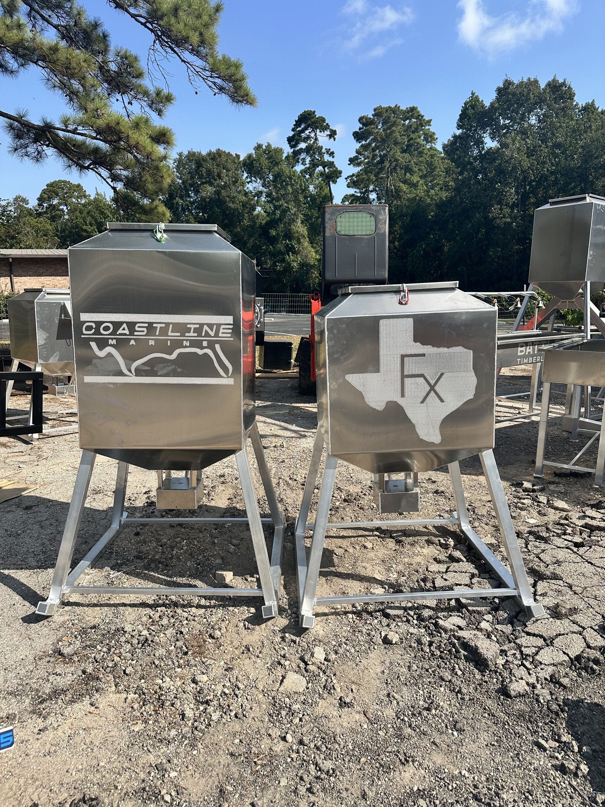 Two custom-etched Aluminum Outfitters corn feeders standing in the New Caney shop yard.