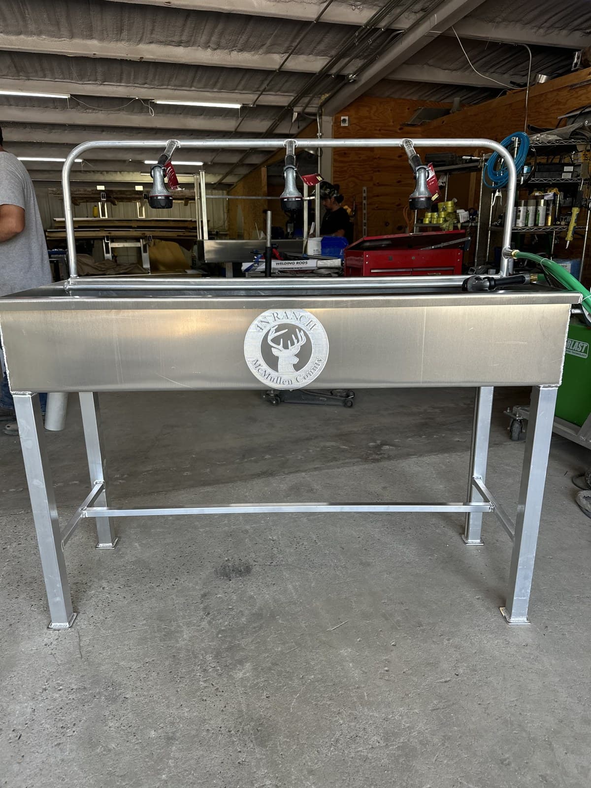 Aluminum cleaning and processing station with a raised trough, spray nozzles and drain.